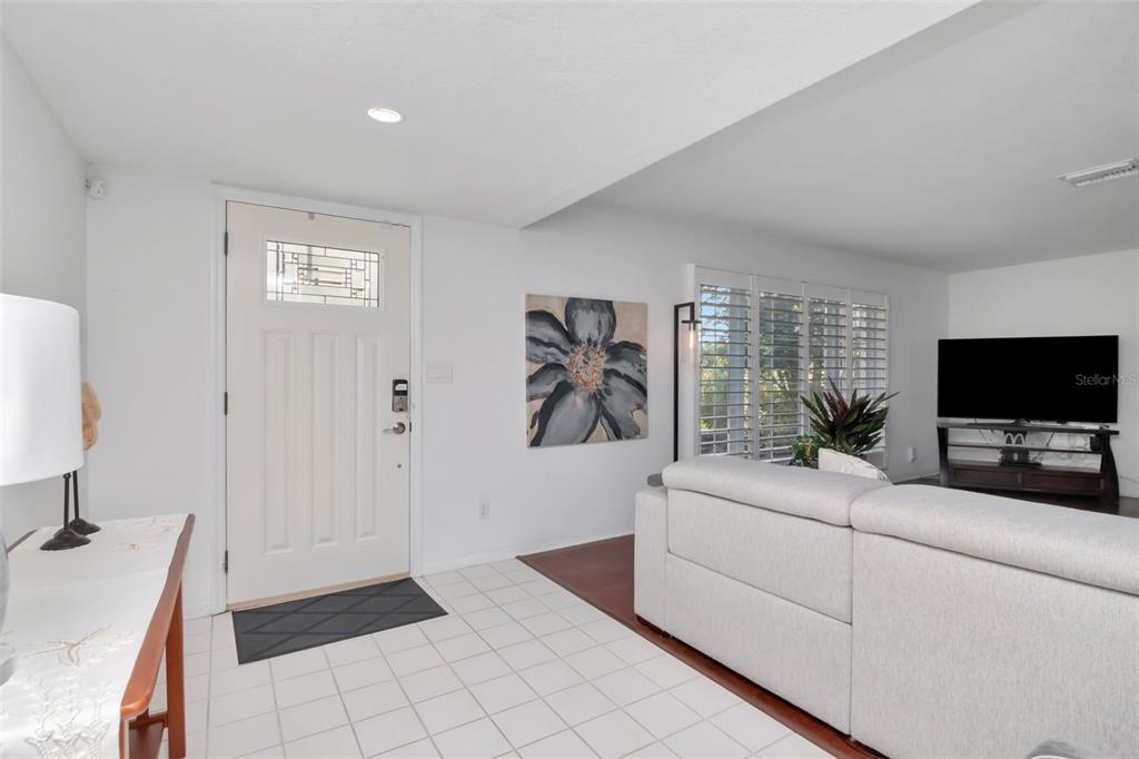 A living room features a white front door, tiled entryway, and a light-colored sectional sofa — 3991 38TH WAY S, ST PETERSBURG, FL
