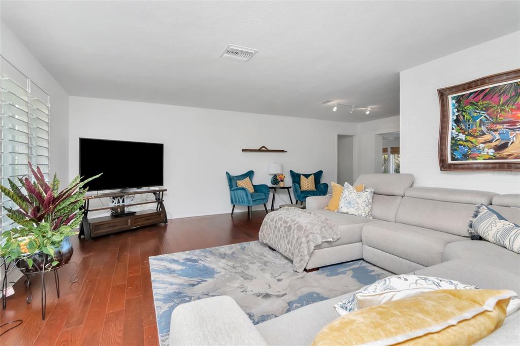 A living room features a grey sectional sofa, two blue armchairs, and a television stand — 3991 38TH WAY S, ST PETERSBURG, FL