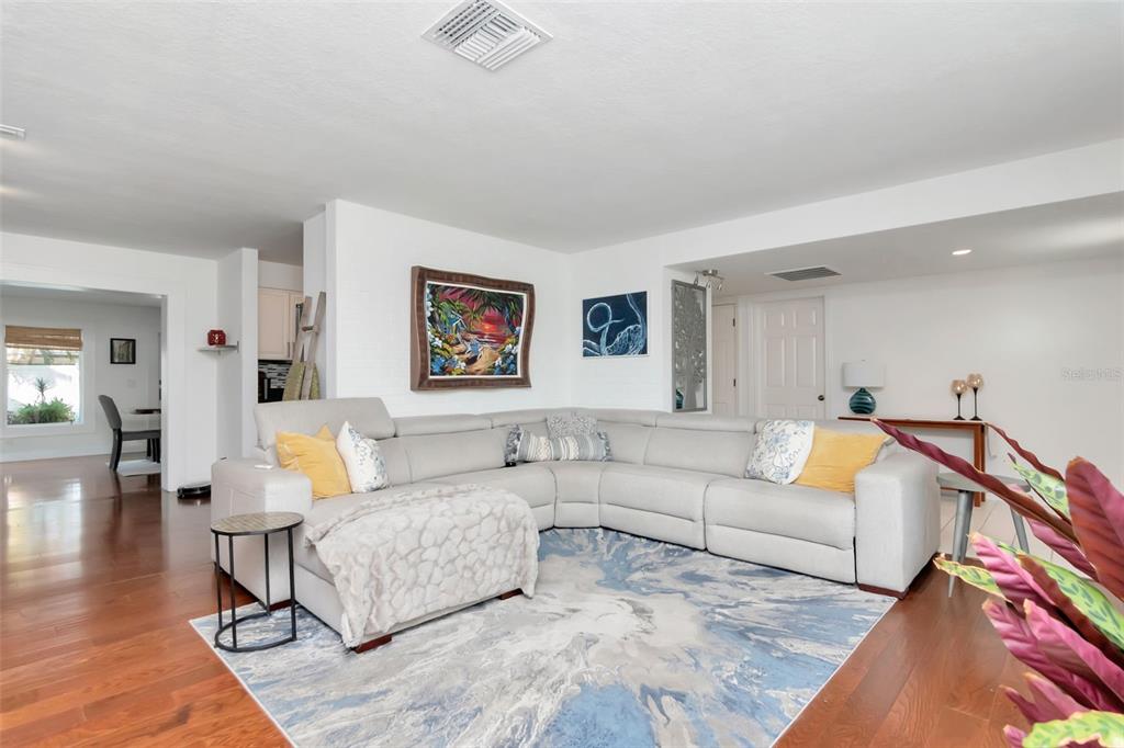 A living room features a large gray sectional sofa, a blue patterned rug, and artwork — 3991 38TH WAY S, ST PETERSBURG, FL