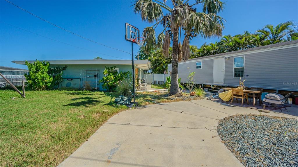 A backyard features a concrete patio, a basketball hoop, and two adjacent mobile homes — 16101 4TH STREET E, REDINGTON BEACH, FL