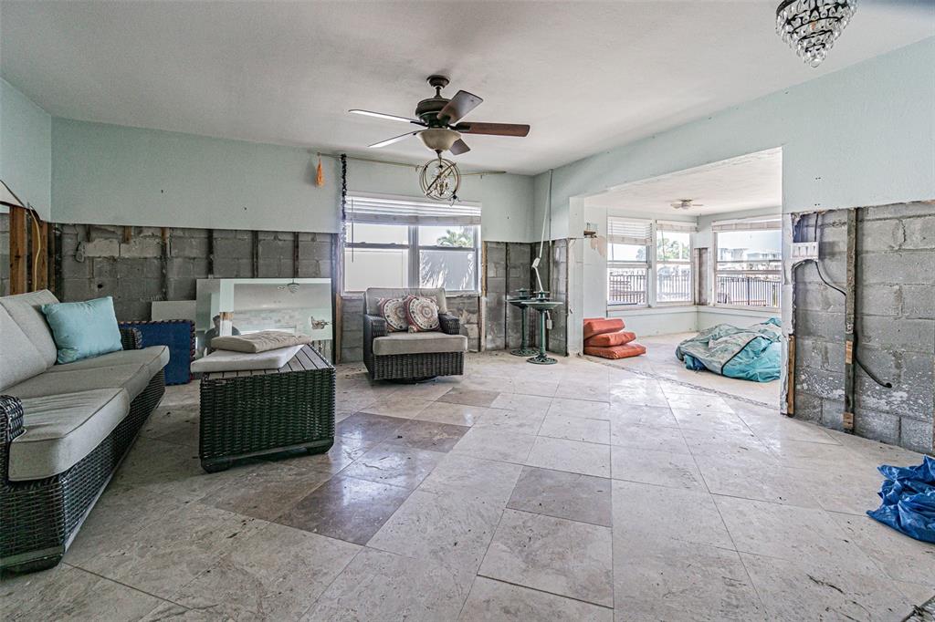 An unfinished living room features exposed concrete block walls, tile flooring, and a ceiling fan — 16101 4TH STREET E, REDINGTON BEACH, FL