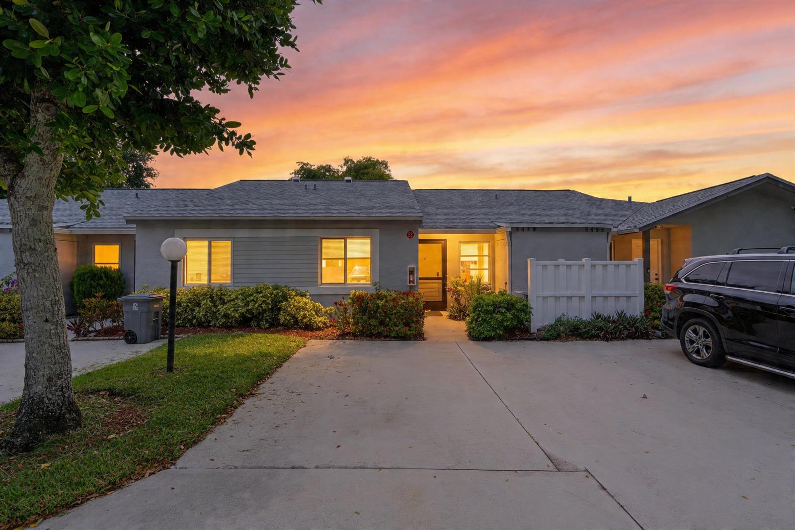A single-story house exterior with a concrete driveway, a black SUV, and a sunset sky — 8955 Windtree Street # C, Boca Raton FL 33496, BOCA RATON, FL
