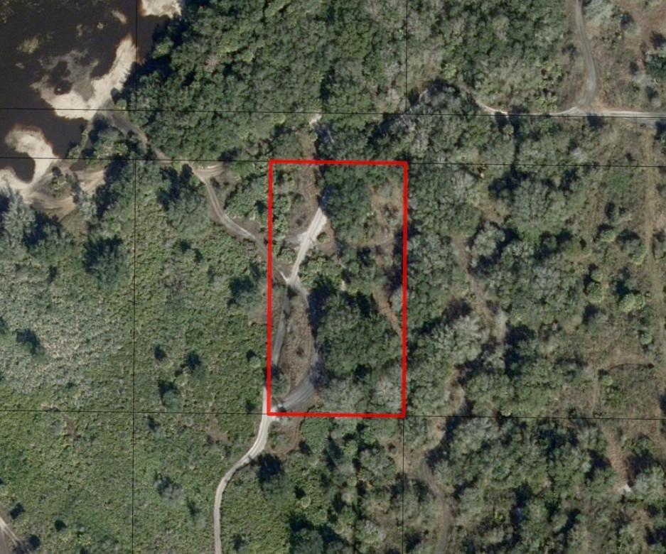 An aerial view shows a rectangular plot of land featuring trees and a dirt road — 0 NW 300th Street, Okeechobee FL 34972, OKEECHOBEE, FL