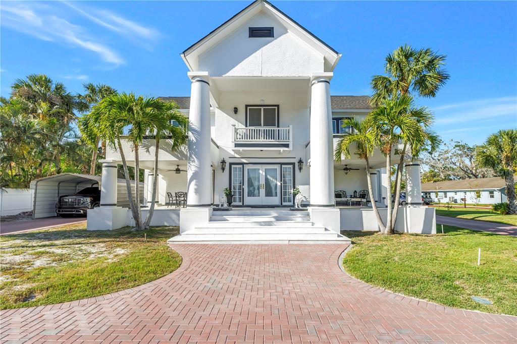 A spacious living room features a grand staircase, a fireplace, and a crystal chandelier — 208 N SPRING BOULEVARD, TARPON SPRINGS, FL