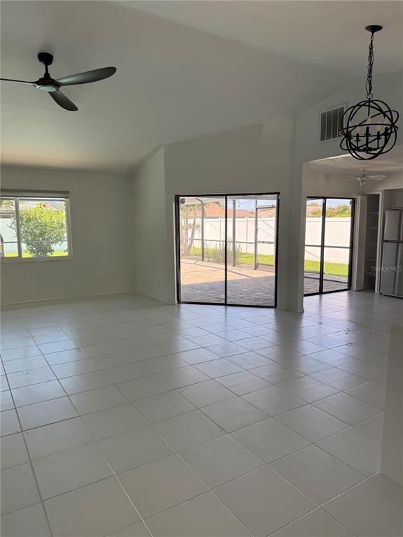 An open-concept living area with white tile floors, a ceiling fan, and sliding glass doors — 32 NE 13TH PLACE, CAPE CORAL, FL