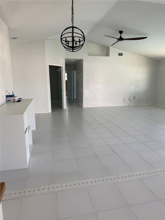 A bright, open-concept living area features white tile flooring, a vaulted ceiling, and a chandelier — 32 NE 13TH PLACE, CAPE CORAL, FL
