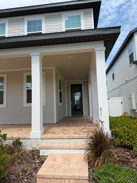 A covered front porch with brick pavers leads to a dark front door — 17658 JAPONICA BLOOM DRIVE, WINTER GARDEN, FL