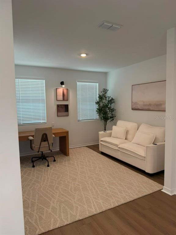 A home office features a desk, a white sofa, a patterned rug, and two windows — 17658 JAPONICA BLOOM DRIVE, WINTER GARDEN, FL