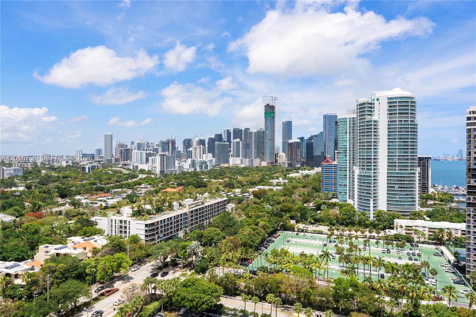 An elevated view of a city skyline with high-rise buildings, lush greenery, and a parking lot — 2475 Brickell Ave # 2206, Miami FL 33129, MIAMI, FL