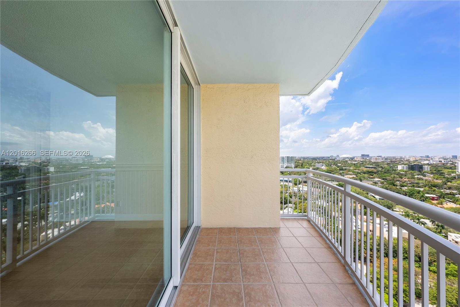 A tiled balcony with a white railing overlooks a city landscape under a blue sky — 2475 Brickell Ave # 2206, Miami FL 33129, MIAMI, FL