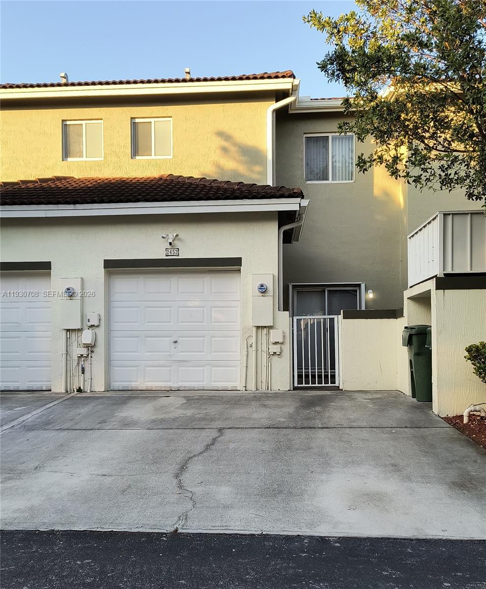 A two-story townhouse exterior features a garage, a gated entrance, and a concrete driveway — 2452 SE 19th Ct, Homestead FL 33035, HOMESTEAD, FL