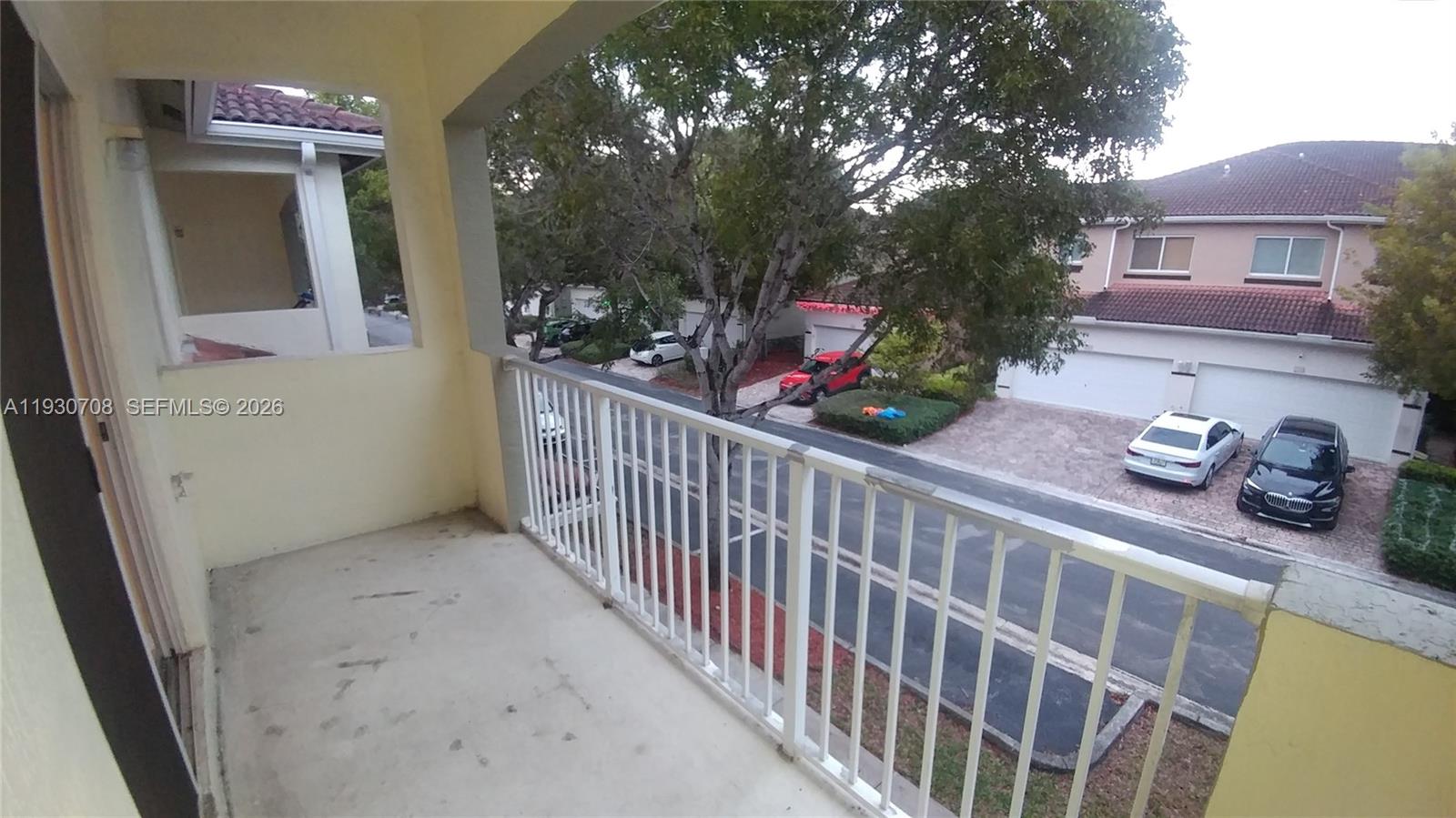 A view from a covered balcony overlooking a residential street with parked cars and trees — 2452 SE 19th Ct, Homestead FL 33035, HOMESTEAD, FL