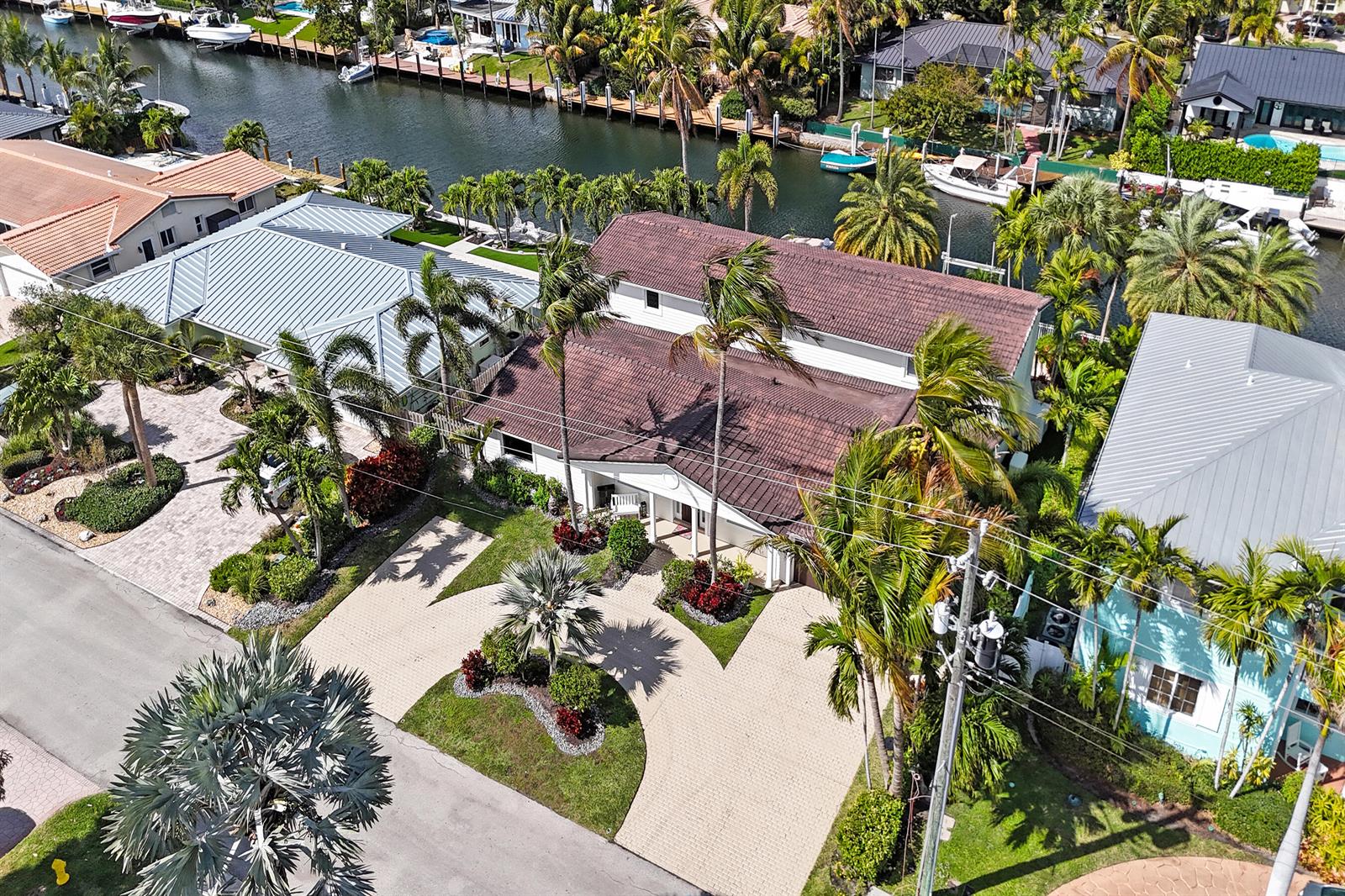 A single-story house with a paved driveway, brown garage door, and palm trees in front — 4011 NE 26th Avenue, Lighthouse Point FL 33064, LIGHTHOUSE POINT, FL