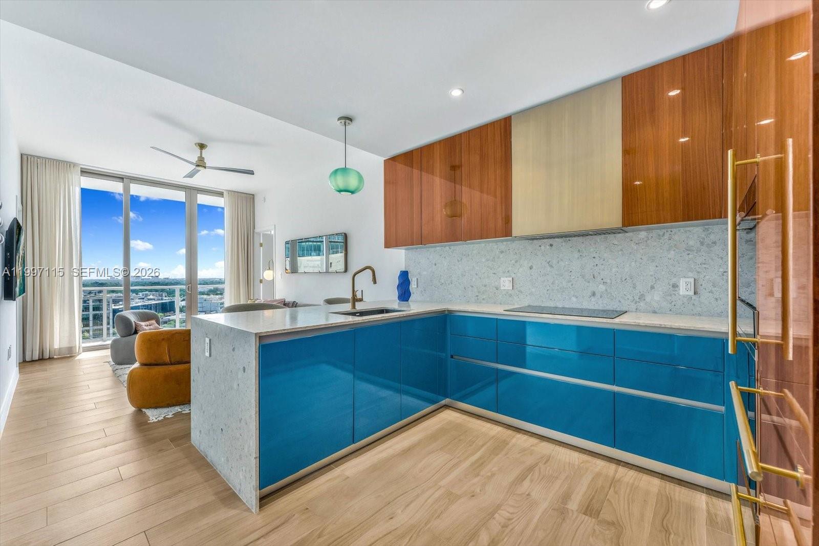 A modern kitchen features blue lower cabinets, wood-toned upper cabinets, and a stone countertop — 2678 Tigertail Ave # 1505, Miami FL 33133, MIAMI, FL