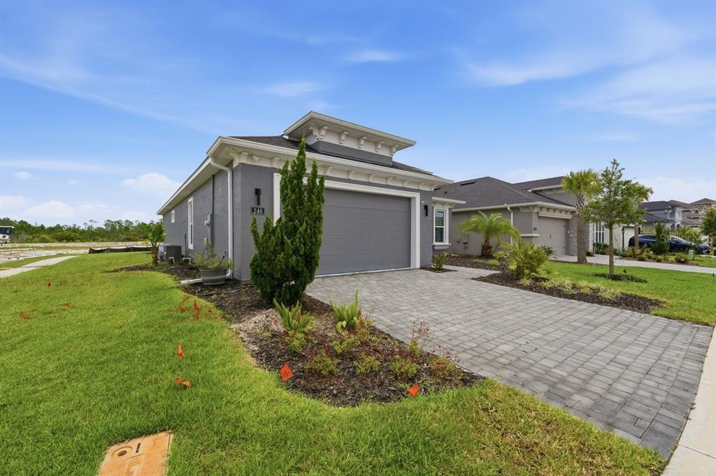 A gray single-story house features a paved driveway, a two-car garage, and landscaped front yard — 246 AZURE MIST WAY, DAYTONA BEACH, FL