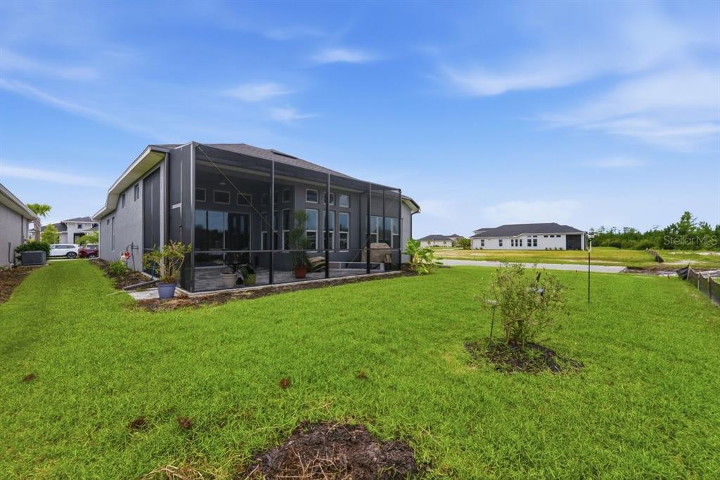 A gray house with a screened-in back patio sits on a grassy lot — 246 AZURE MIST WAY, DAYTONA BEACH, FL