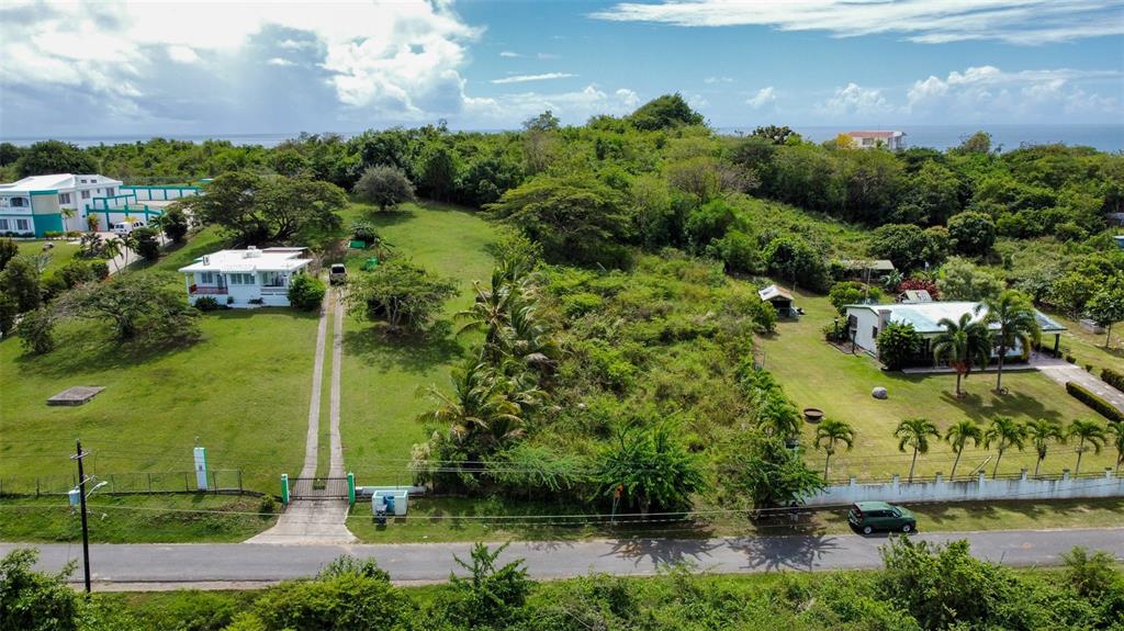 An aerial view shows two houses separated by a large, undeveloped grassy lot — 63 ROUTE 201, VIEQUES, PR
