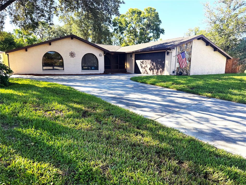 A single-story house with a stucco exterior, arched windows, and a two-car garage — 7041 MAYHILL COURT, SPRING HILL, FL