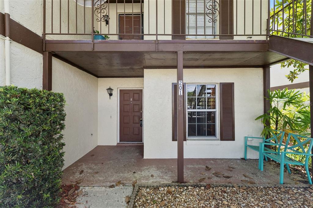 The exterior view shows a ground-floor apartment entrance with a brown door and patio area — 600 NORTHERN WAY UNIT 201, WINTER SPRINGS, FL