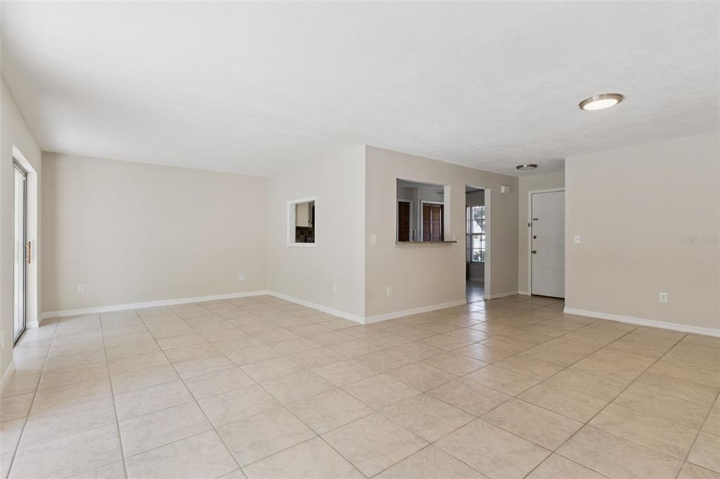 An open-concept living and dining area features neutral walls, tile flooring, and modern furniture — 600 NORTHERN WAY UNIT 201, WINTER SPRINGS, FL