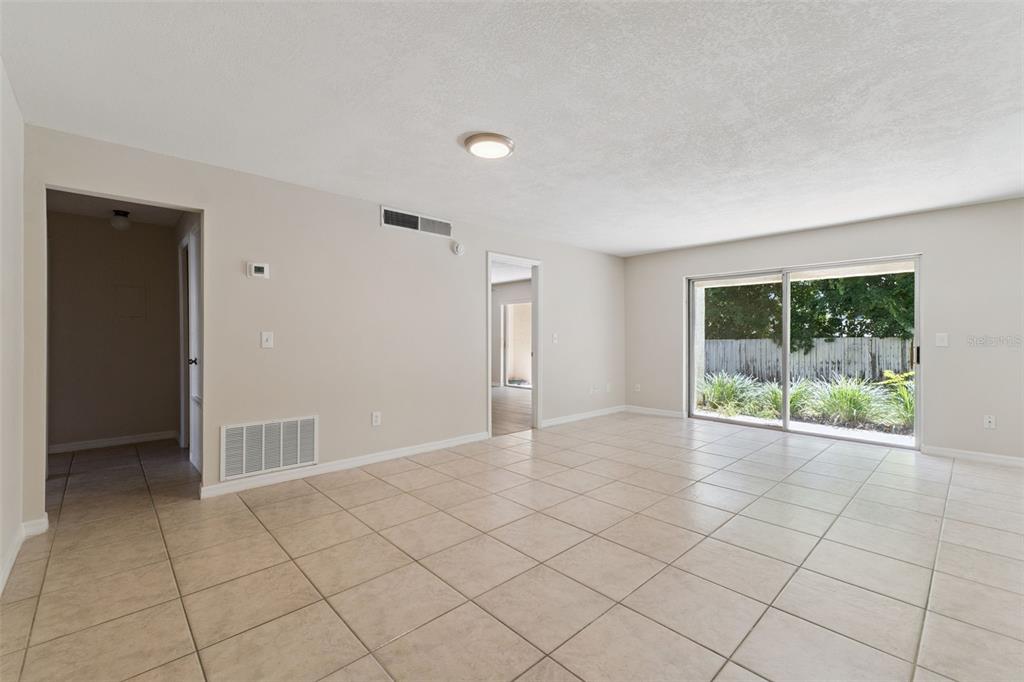 An open-concept living area features light-colored tile flooring, beige walls, and a kitchen pass-through window — 600 NORTHERN WAY UNIT 201, WINTER SPRINGS, FL