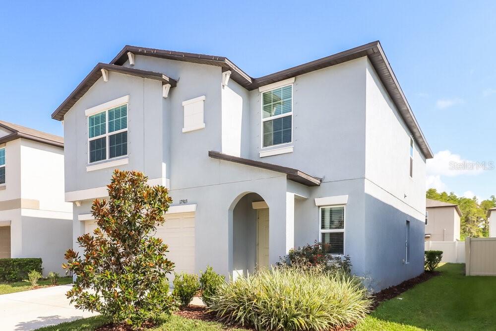 A two-story light blue house with a garage and a small front yard — 17903 BLISSFUL STARS DRIVE, LUTZ, FL