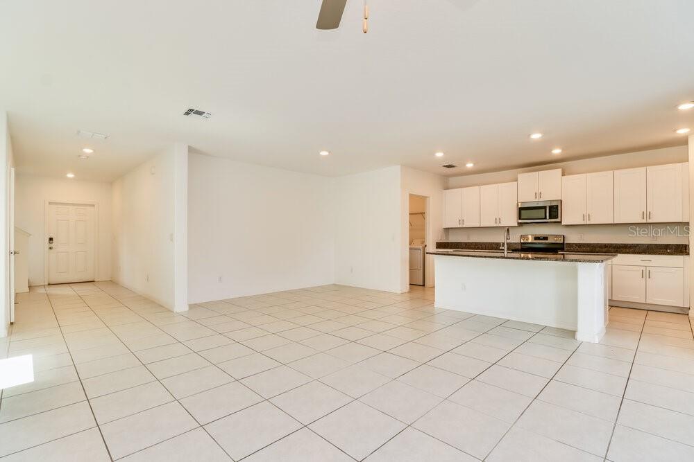 An open-concept kitchen and living area features white cabinetry, granite countertops, and tile flooring — 17903 BLISSFUL STARS DRIVE, LUTZ, FL
