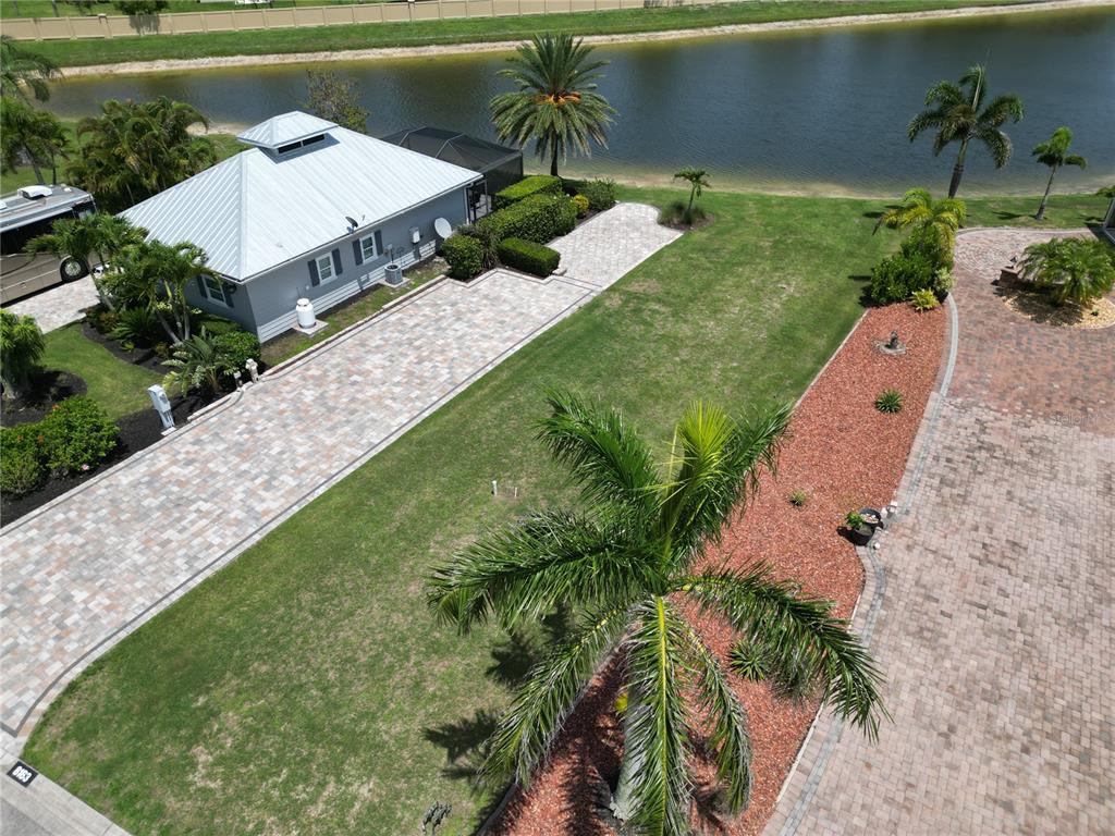 An aerial view shows a paved driveway, a small house, and a lawn by a lake — 8163 SW SAND CRANE CIRCLE LOT 6, ARCADIA, FL