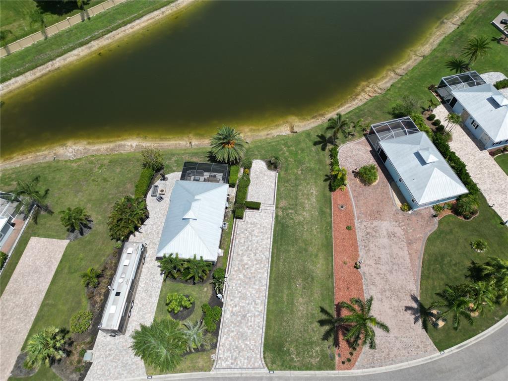 An aerial view shows two houses with paved driveways and screened lanais near a pond — 8163 SW SAND CRANE CIRCLE LOT 6, ARCADIA, FL