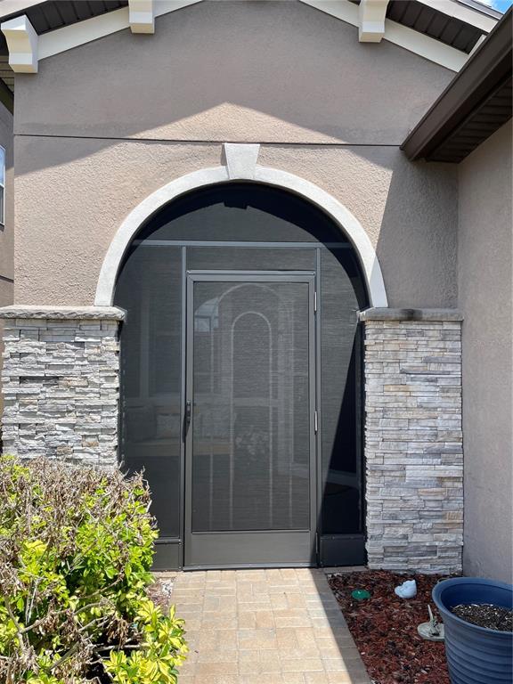 A front entryway features a screened door set within a stone-accented arched frame — 436 PONTEVEDRA ROAD, DAVENPORT, FL
