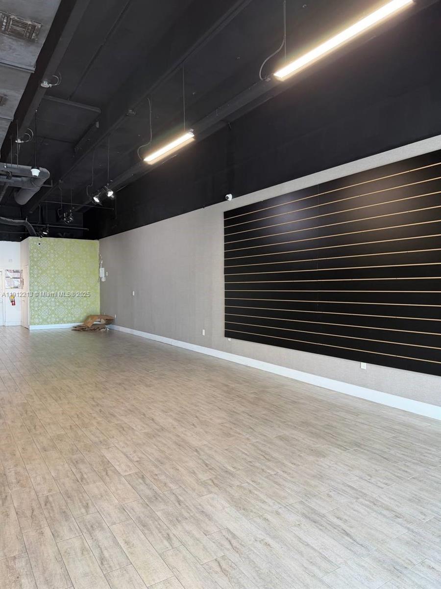 An empty retail space features light wood-look flooring, a black slat wall, and exposed ceilings — 2621 NW 79th Ave, Doral FL 33122, DORAL, FL