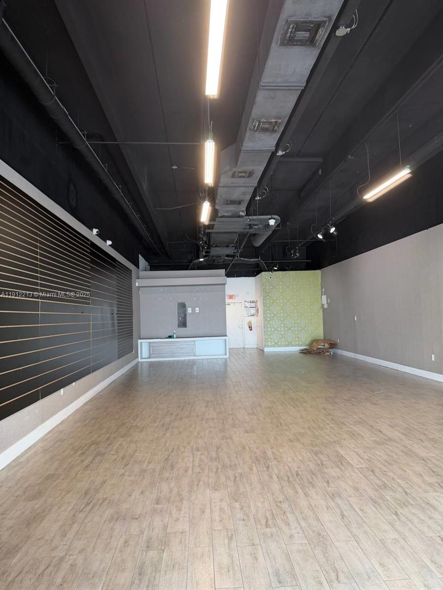 An empty commercial space features a black ceiling, wood-look tile flooring, and slat wall panels — 2621 NW 79th Ave, Doral FL 33122, DORAL, FL