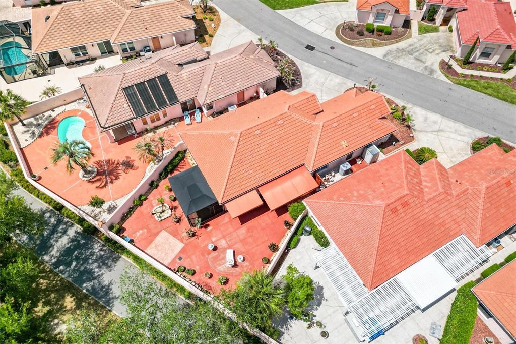 An aerial view shows several houses with red tile roofs, swimming pools, and paved patios — 1314 SANTA ROSA COURT, LADY LAKE, FL
