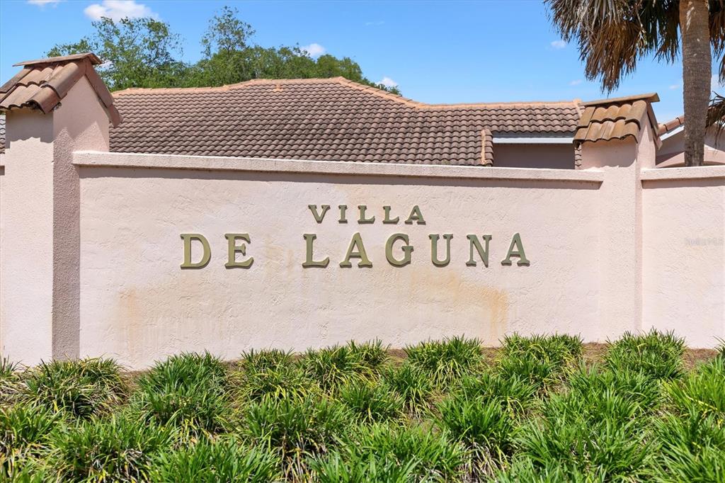 A beige stucco wall displays the text Villa De Laguna in front of a house — 1314 SANTA ROSA COURT, LADY LAKE, FL