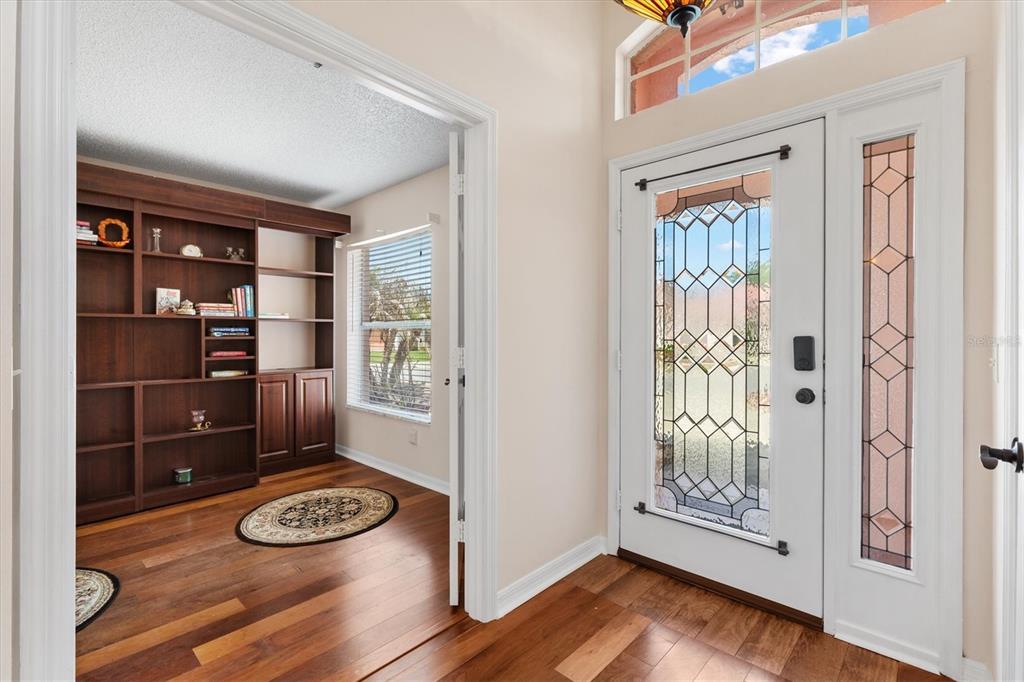An entryway with hardwood floors leads to a home office featuring built-in wooden bookshelves — 1314 SANTA ROSA COURT, LADY LAKE, FL