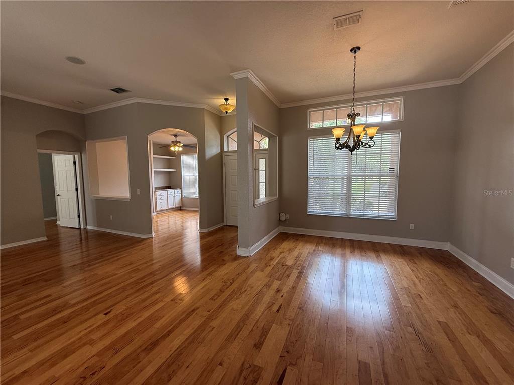 An empty room with hardwood floors, a chandelier, and a view into an adjacent hallway — 3045 SUTTON WOODS DRIVE, PLANT CITY, FL