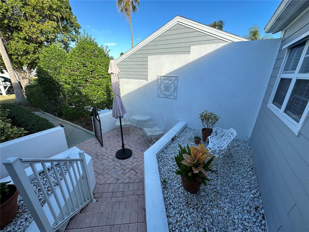A paved patio area features a small table, chairs, an umbrella, and white gravel landscaping — 517 WOODSTORK CIRCLE, BRADENTON, FL