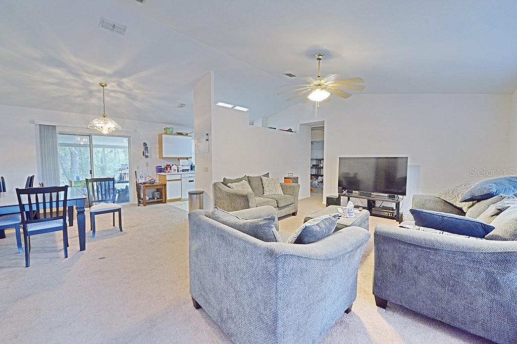 A living room with gray furniture, a television, and an adjacent dining area — 5025 S HUMMINGBIRD AVENUE, INVERNESS, FL