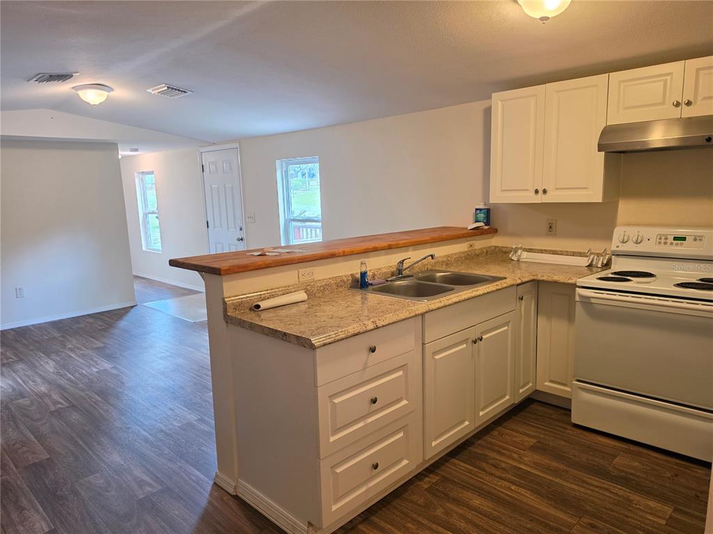 A kitchen with white cabinets, granite countertops, and a wood-topped breakfast bar overlooks a living area — 6708 W CHERRYWOOD COURT, CRYSTAL RIVER, FL
