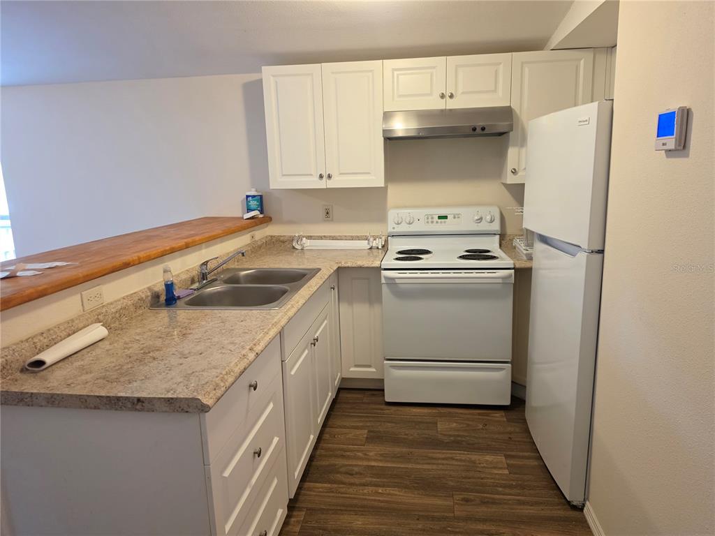 A kitchen features white cabinets, a white stove, a refrigerator, and a wood-topped breakfast bar — 6708 W CHERRYWOOD COURT, CRYSTAL RIVER, FL