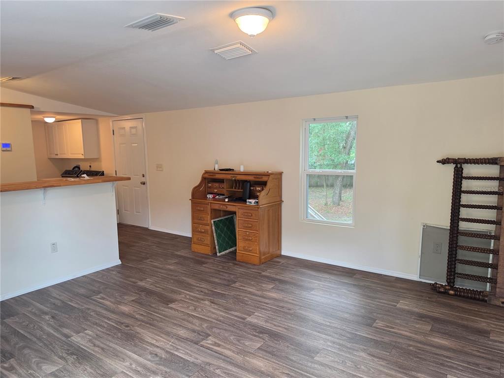 A living room with wood-look flooring, a wooden roll-top desk, and a kitchen breakfast bar — 6708 W CHERRYWOOD COURT, CRYSTAL RIVER, FL