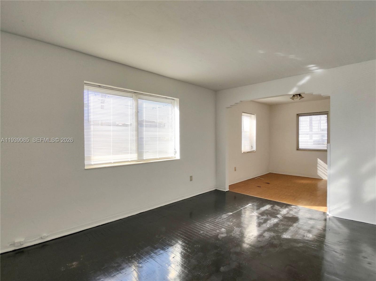 A living room with dark hardwood floors transitions into a dining area with light flooring — 1565 SW 6th St, Miami FL 33135, MIAMI, FL