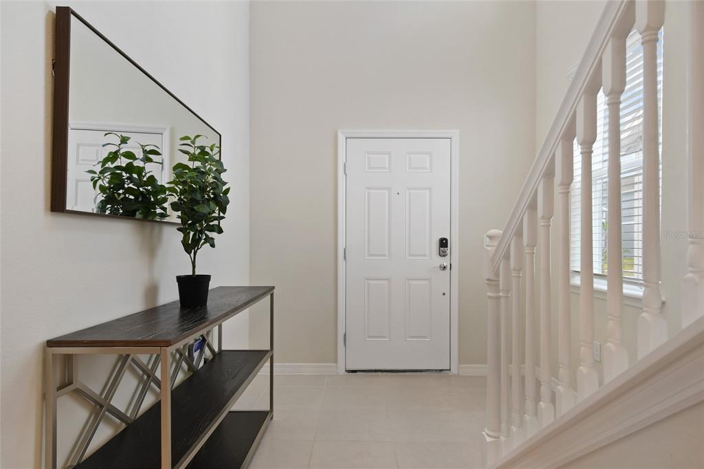 An entryway features a console table, a mirror, and a staircase with a white railing — 4428 KAIPO ROAD, DAVENPORT, FL