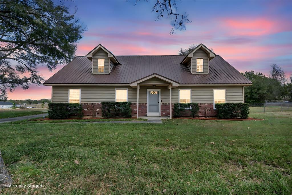 A one-story house with a metal roof, dormer windows, and a brick-accented exterior — 9610 NELLIE HILLS COURT, CLERMONT, FL