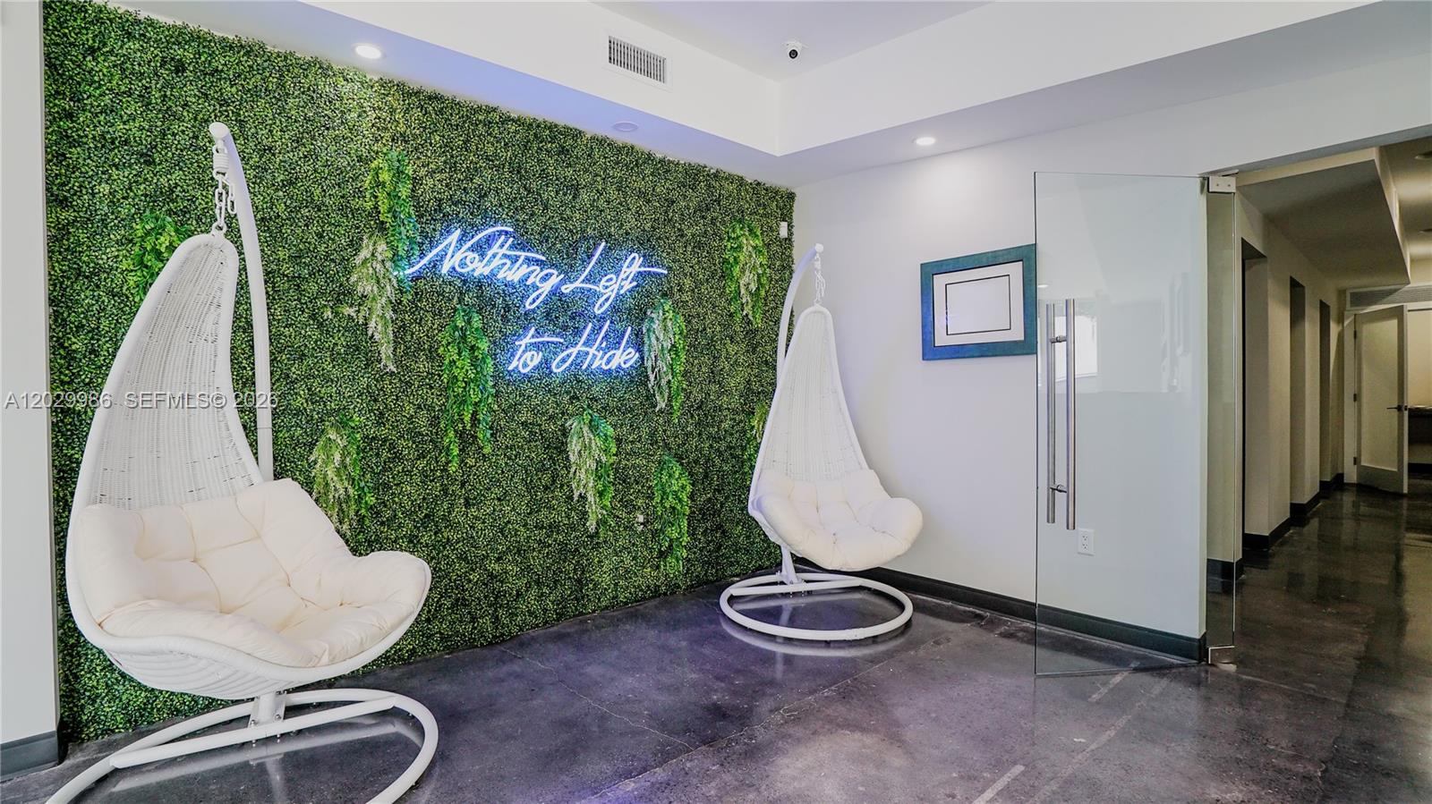 A waiting area features two white hanging chairs against a green wall with neon signage — 530 NW 54th St, Miami FL 33127, MIAMI, FL