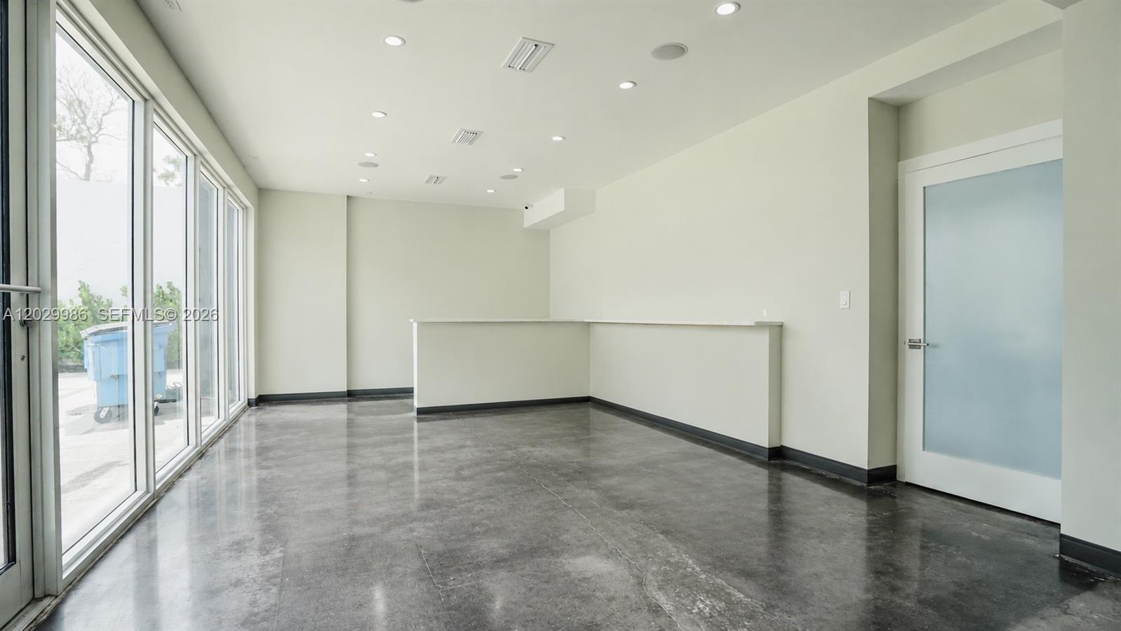 An empty room features polished concrete floors, recessed lighting, a built-in counter, and glass doors — 530 NW 54th St, Miami FL 33127, MIAMI, FL