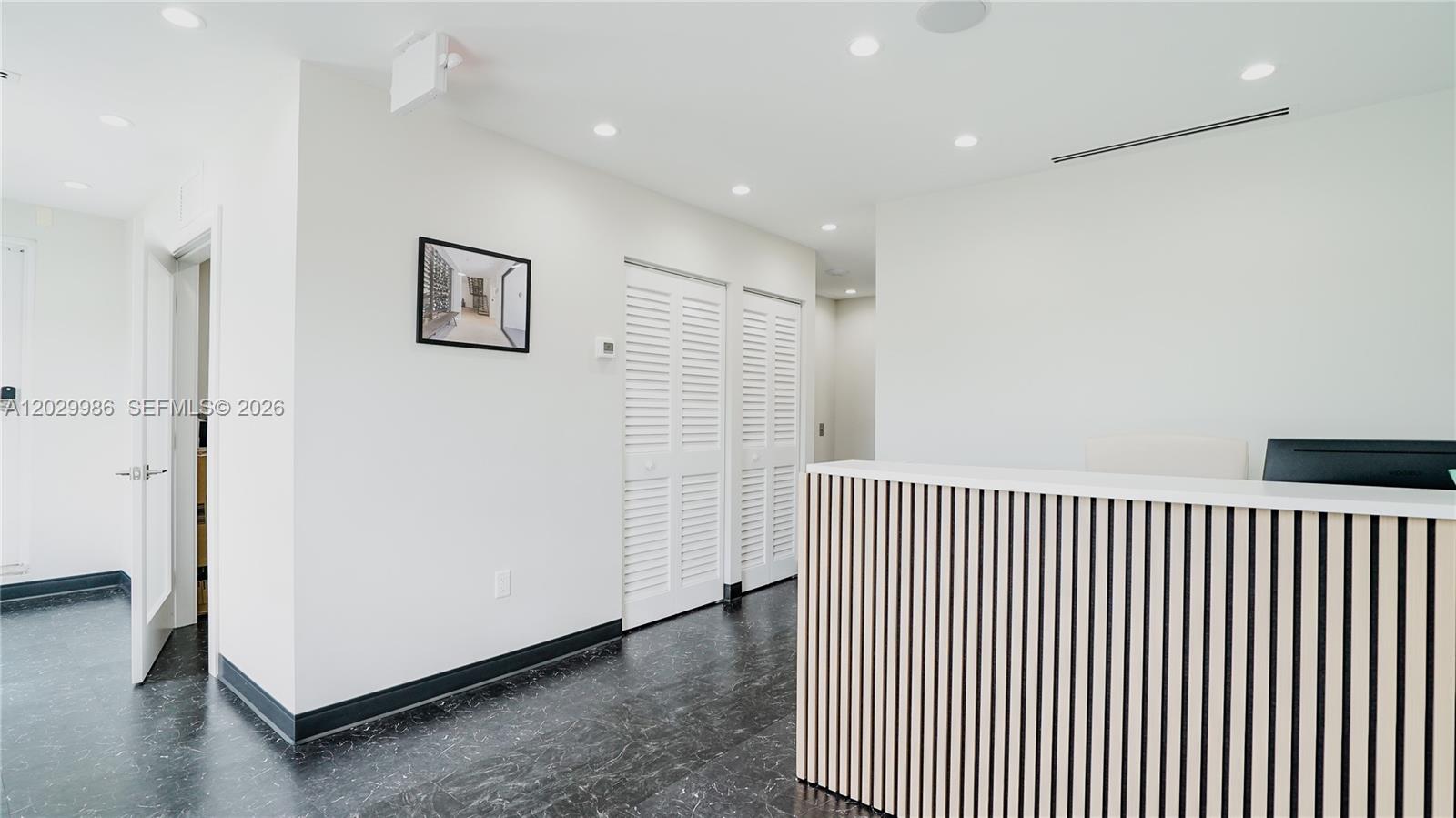 A reception area features a slatted wood desk, white walls, and dark marble-patterned flooring — 530 NW 54th St, Miami FL 33127, MIAMI, FL
