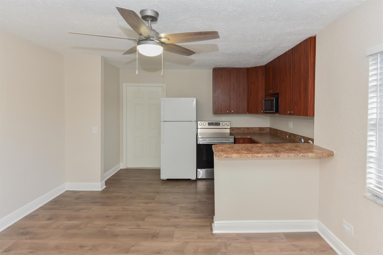 A kitchen features wood-look flooring, dark wood cabinets, stainless steel appliances, and a breakfast bar — 605 N Federal Highway # 9, FL 33460, FL