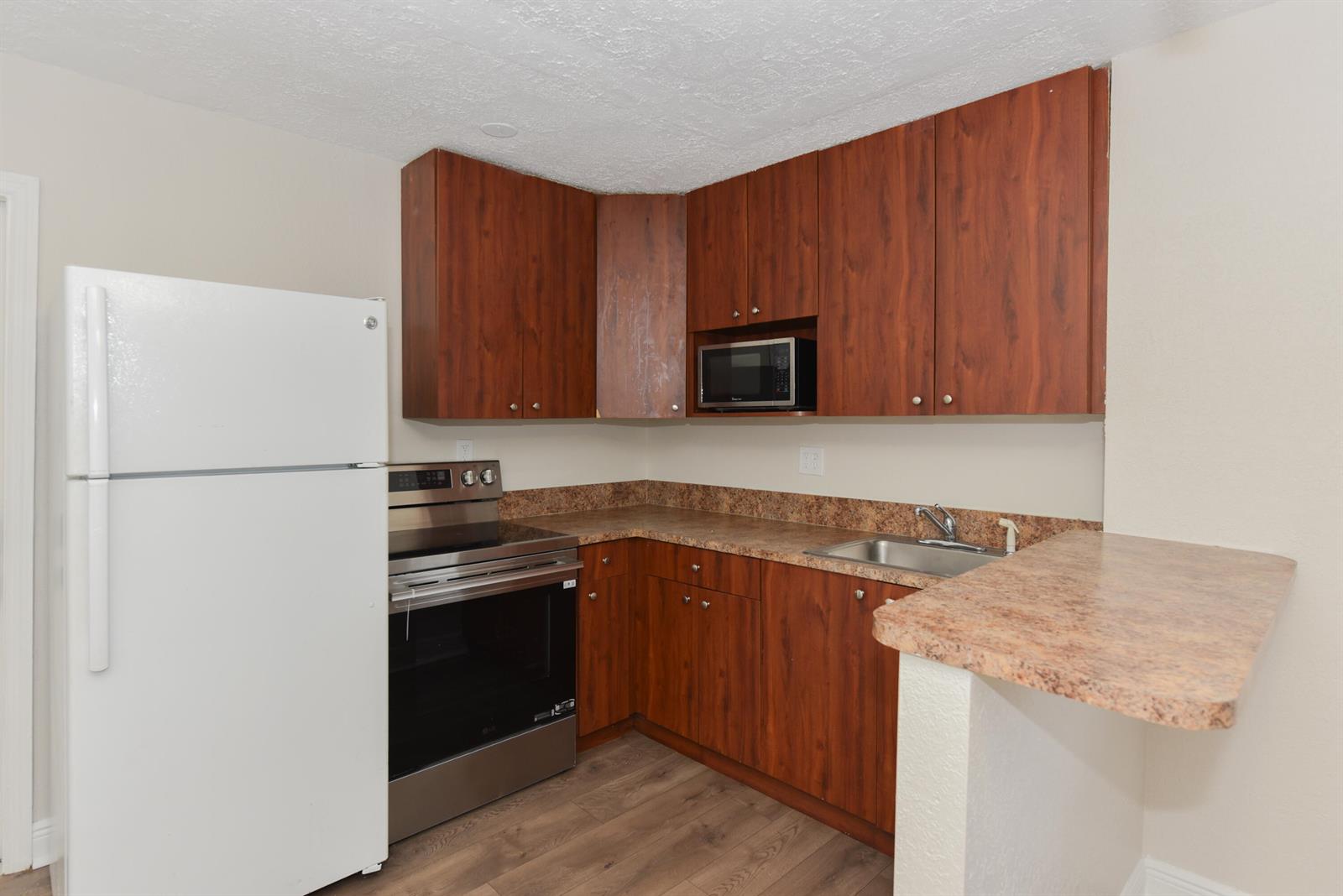 A kitchen features wood-grain cabinets, stainless steel appliances, and a laminate countertop — 605 N Federal Highway # 9, FL 33460, FL
