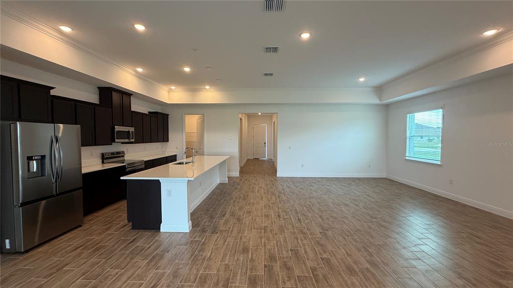 A kitchen with dark cabinets, a large white island, and wood-look tile flooring — 4378 WINESAP WAY, LAKELAND, FL